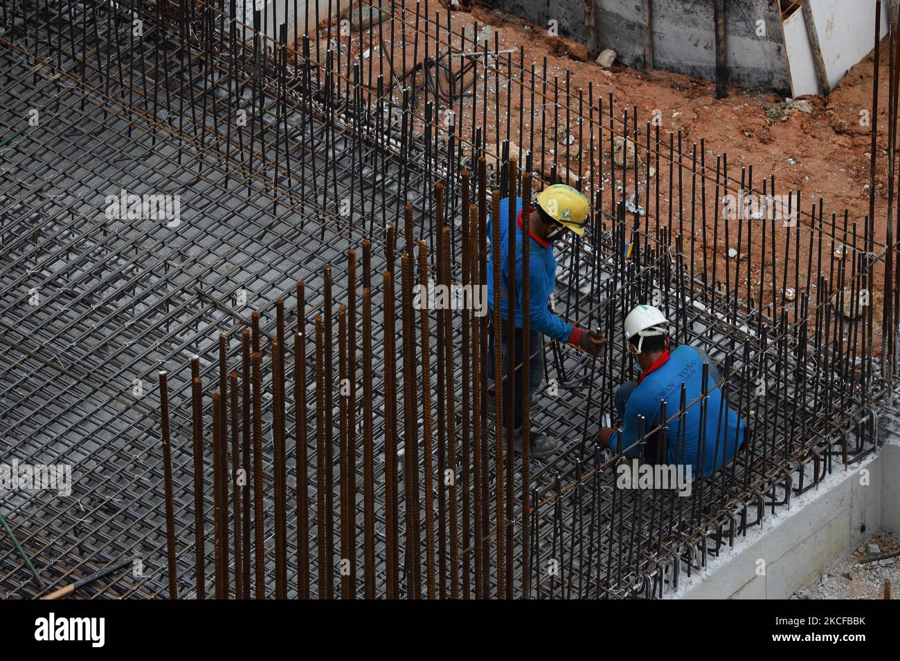 Migrant workers work at a building construction site on May 29, 2021 in Singapore. Singapore enters a month long heightened alert from May 16 to June 13 to curb the spread of COVID-19 cases in the local community. New restrictions on movements and activities have been introduced such as limiting social interaction to two, prohibiting dining out and a reduced operating capacity at shopping malls, offices and attractions. On May 17, the construction industry stakeholders appealed to Multi-Ministry Taskforce to bring in foreign workers in a safe and controlled manner after the built environment i Stock Photo