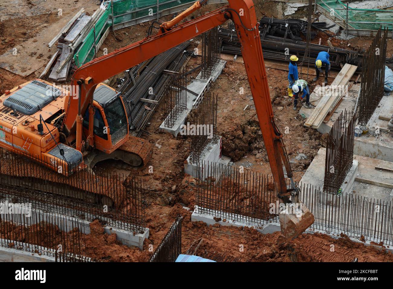 Migrant workers work at a building construction site on May 29, 2021 in Singapore. Singapore enters a month long heightened alert from May 16 to June 13 to curb the spread of COVID-19 cases in the local community. New restrictions on movements and activities have been introduced such as limiting social interaction to two, prohibiting dining out and a reduced operating capacity at shopping malls, offices and attractions. On May 17, the construction industry stakeholders appealed to Multi-Ministry Taskforce to bring in foreign workers in a safe and controlled manner after the built environment i Stock Photo