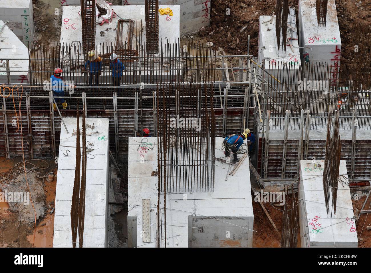 Migrant workers work at a building construction site on May 29, 2021 in Singapore. Singapore enters a month long heightened alert from May 16 to June 13 to curb the spread of COVID-19 cases in the local community. New restrictions on movements and activities have been introduced such as limiting social interaction to two, prohibiting dining out and a reduced operating capacity at shopping malls, offices and attractions. On May 17, the construction industry stakeholders appealed to Multi-Ministry Taskforce to bring in foreign workers in a safe and controlled manner after the built environment i Stock Photo