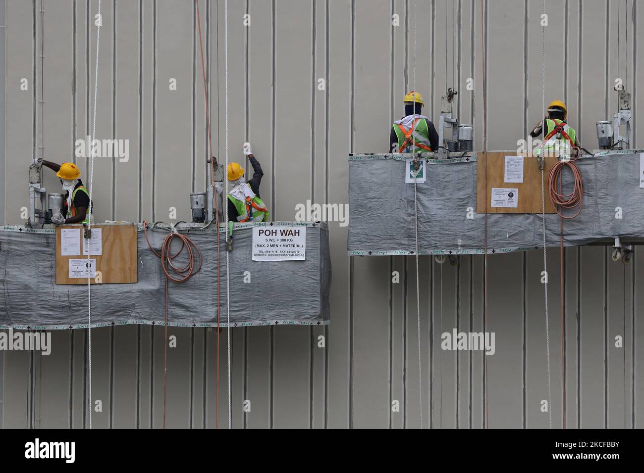 Migrant workers work at a building construction site on May 29, 2021 in Singapore. Singapore enters a month long heightened alert from May 16 to June 13 to curb the spread of COVID-19 cases in the local community. New restrictions on movements and activities have been introduced such as limiting social interaction to two, prohibiting dining out and a reduced operating capacity at shopping malls, offices and attractions. On May 17, the construction industry stakeholders appealed to Multi-Ministry Taskforce to bring in foreign workers in a safe and controlled manner after the built environment i Stock Photo