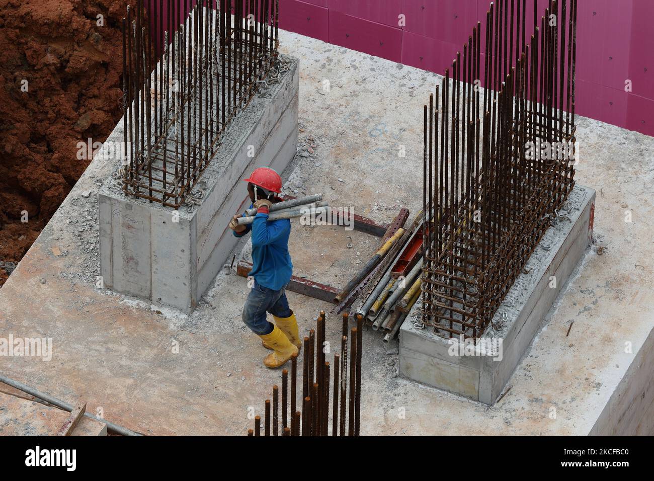 A migrant worker works at a building construction site on May 29, 2021 in Singapore. Singapore enters a month long heightened alert from May 16 to June 13 to curb the spread of COVID-19 cases in the local community. New restrictions on movements and activities have been introduced such as limiting social interaction to two, prohibiting dining out and a reduced operating capacity at shopping malls, offices and attractions. On May 17, the construction industry stakeholders appealed to Multi-Ministry Taskforce to bring in foreign workers in a safe and controlled manner after the built environment Stock Photo