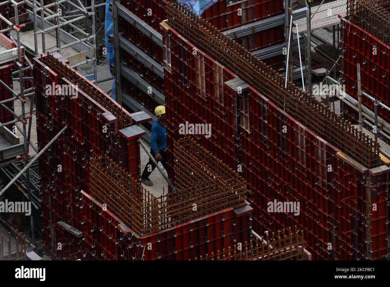 A migrant worker works at a building construction site on May 29, 2021 in Singapore. Singapore enters a month long heightened alert from May 16 to June 13 to curb the spread of COVID-19 cases in the local community. New restrictions on movements and activities have been introduced such as limiting social interaction to two, prohibiting dining out and a reduced operating capacity at shopping malls, offices and attractions. On May 17, the construction industry stakeholders appealed to Multi-Ministry Taskforce to bring in foreign workers in a safe and controlled manner after the built environment Stock Photo