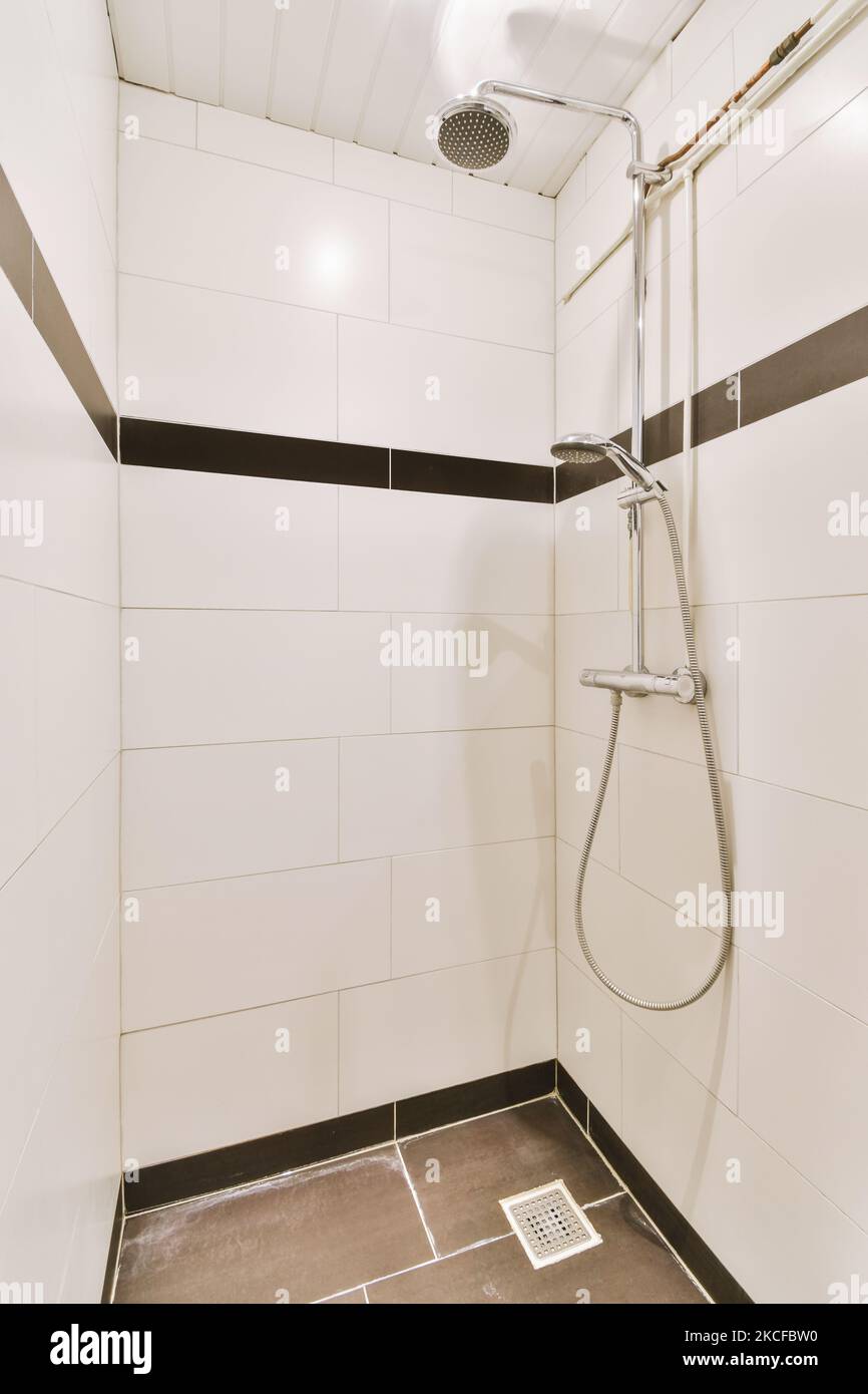 Bathroom with white tiled walls and open shower near sink with toilet