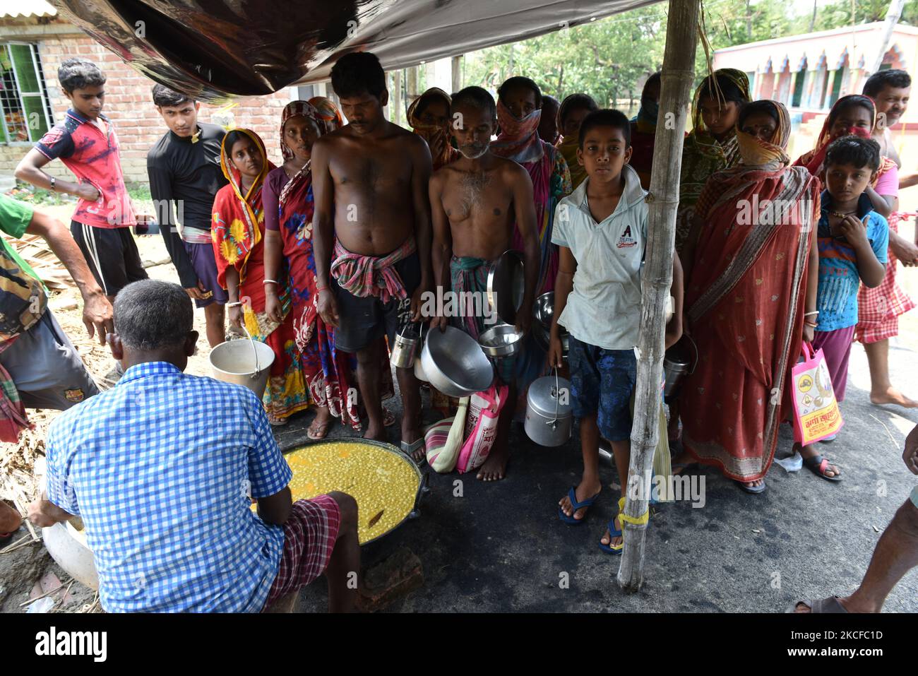 Villagers gathered to collect food in a village relief camp. On May 28, 2021 in West Bengal, India. According to report more than three hundred thousand homes were destroyed and the people directly were affected by the severe cyclone Yaas, as sea waters along the Bengal coast and rivers started swelling and breached embankments, after the landfall at Odisha at 9.30am on 26 May 2021. Various farms were directly affected by the salt water reached in the farming areas. The cities narrowly escaped from the cyclone hit but remaining coastal areas are in severe condition. (Photo by Sukhomoy Sen/NurP Stock Photo