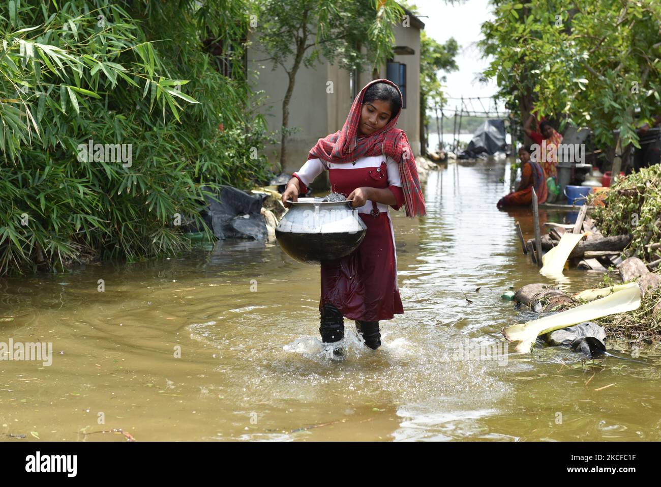 A girl carrying drinking water from the only left tube well. All other handpumps are completely under water right now. On May 28, 2021 in West Bengal, India. According to report more than three hundred thousand homes were destroyed and the people directly were affected by the severe cyclone Yaas, as sea waters along the Bengal coast and rivers started swelling and breached embankments, after the landfall at Odisha at 9.30am on 26 May 2021. Various farms were directly affected by the salt water reached in the farming areas. The cities narrowly escaped from the cyclone hit but remaining coastal  Stock Photo