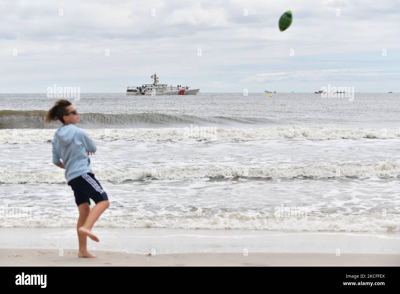 After the entire weekend of shows were canceled due to heavy storms, an improvised Memorial Day airshow was held at New York's Jones Beach, featuring World War 2 aircraft from the American Airpower Museum and the U.S. Air Force Thunderbirds. Here, a boy plays football on the beach in front of the Coast Guard cutter Bruckenthal on 31 May 2021 in New York, US. (Photo by B.A. Van Sise/NurPhoto) Stock Photo