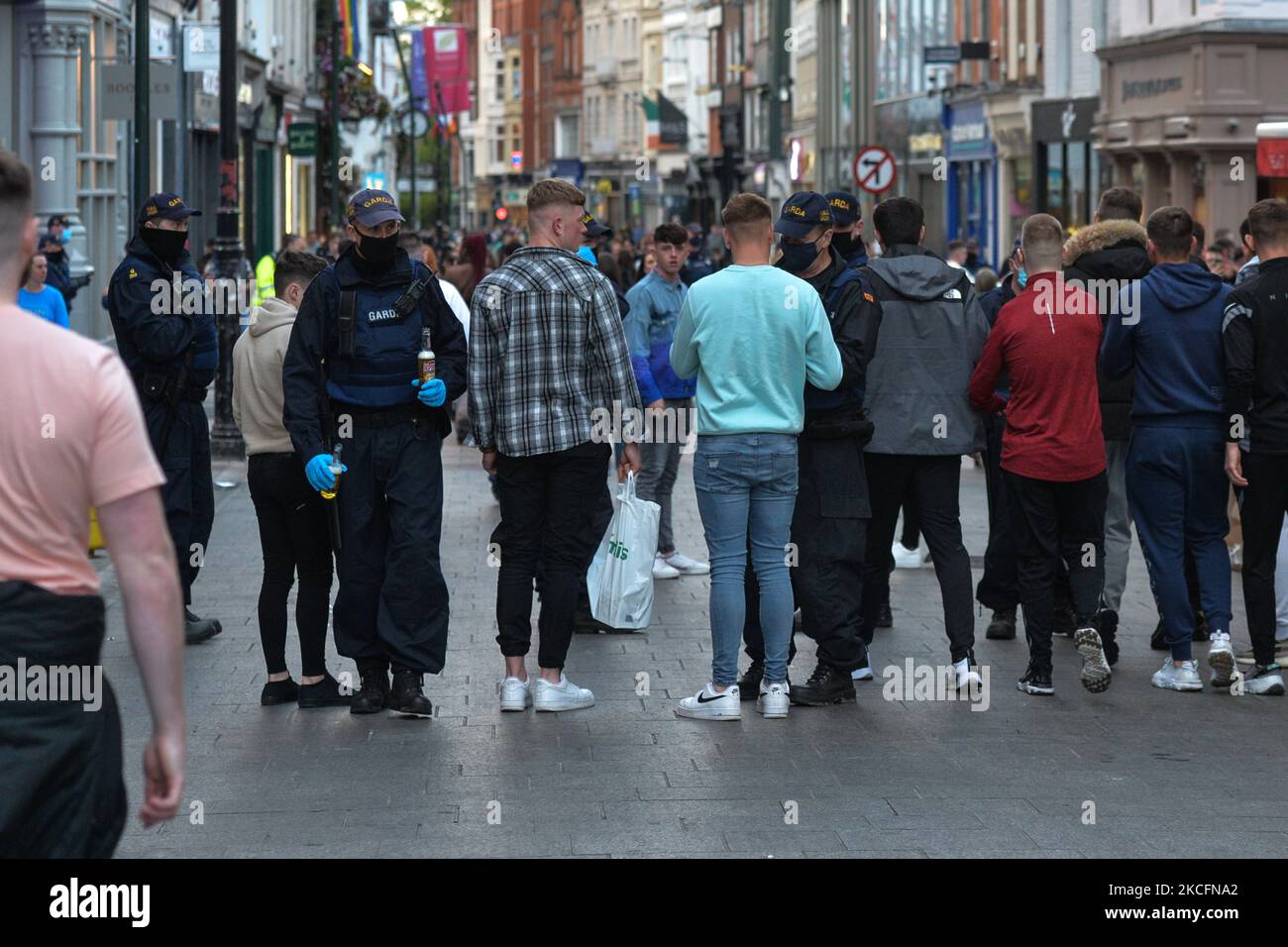 Members of Gardai checking a group of young men and confiscate alcohol on Grafton Street in Dublin city center on Saturday evening, June 5, 2021. Nineteen people were arrested on suspicion of violating public order after another night of rioting in downtown Dublin. Glass bottles and other missiles were thrown at the gardai after they collided with large crowds in the city on Saturday night. On Sunday, 6 June 2021, in Dublin, Ireland. (Photo by Artur Widak/NurPhoto) Stock Photo