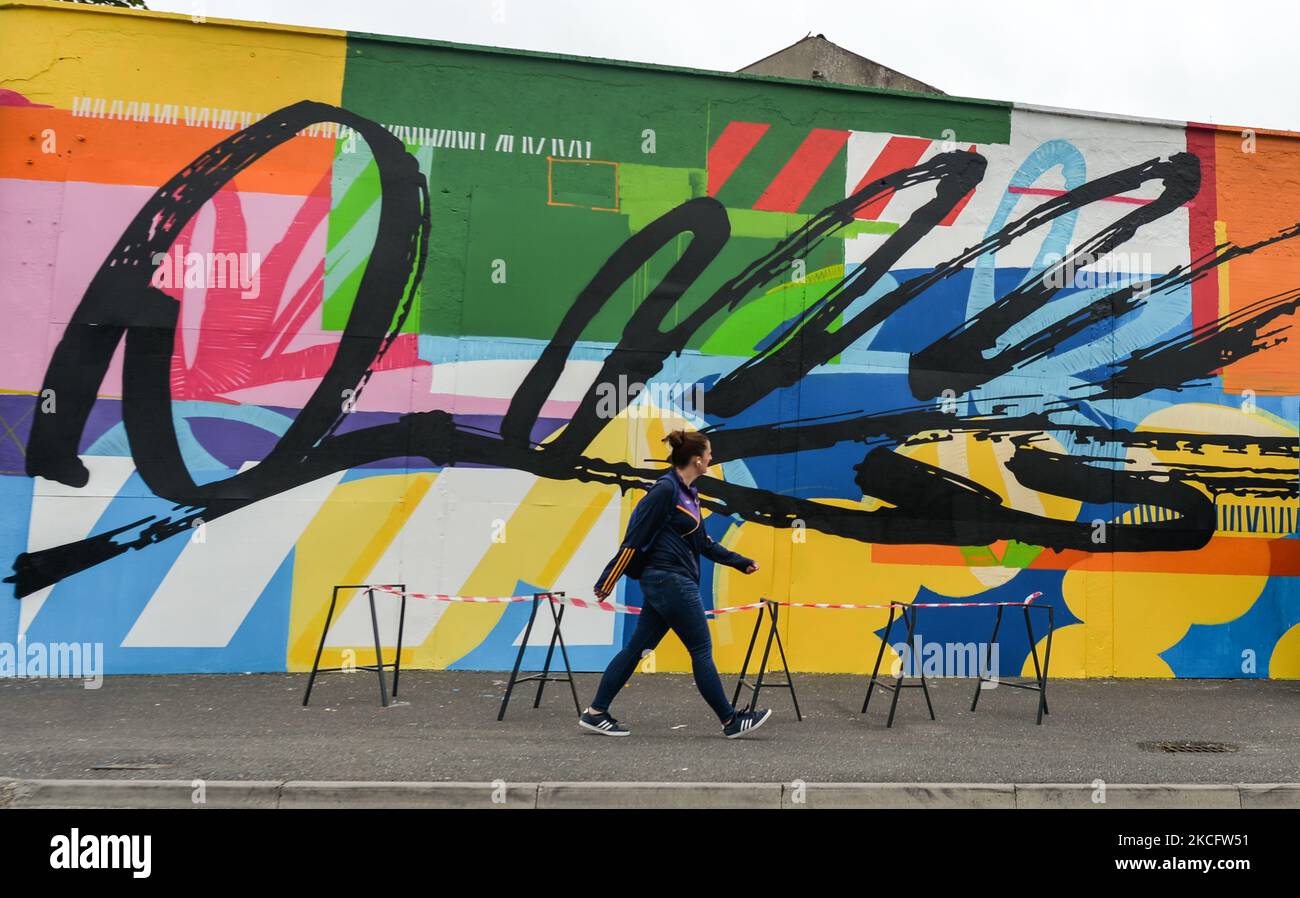 A woman walks by a new mural by Irish artist Maser, located at the