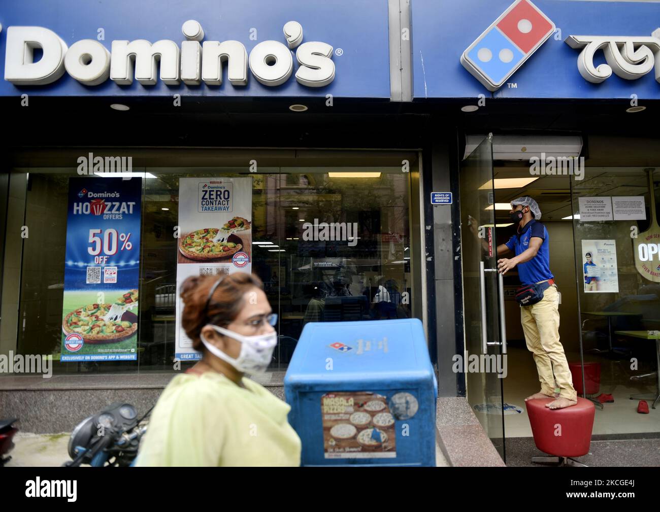 A cleaning staff of Dominos cleans a glass door before it opens for the day amid Coronavirus emergency in Kolkata, India, 24 June, 2021. (Photo by Indranil Aditya/NurPhoto) Stock Photo