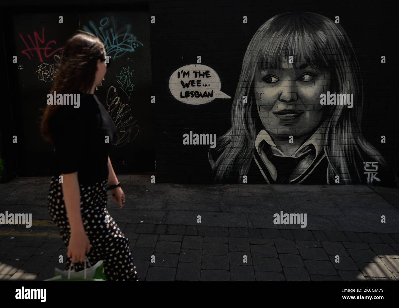 A lady walks past a mural representing the fictional character Clare Devlin from the TV show 'Derry Girls' by ESTR (Emmalene Blake), in Dublin city center. On Tuesday, 29 June 2021, in Dublin, Ireland. (Photo by Artur Widak/NurPhoto) Stock Photo