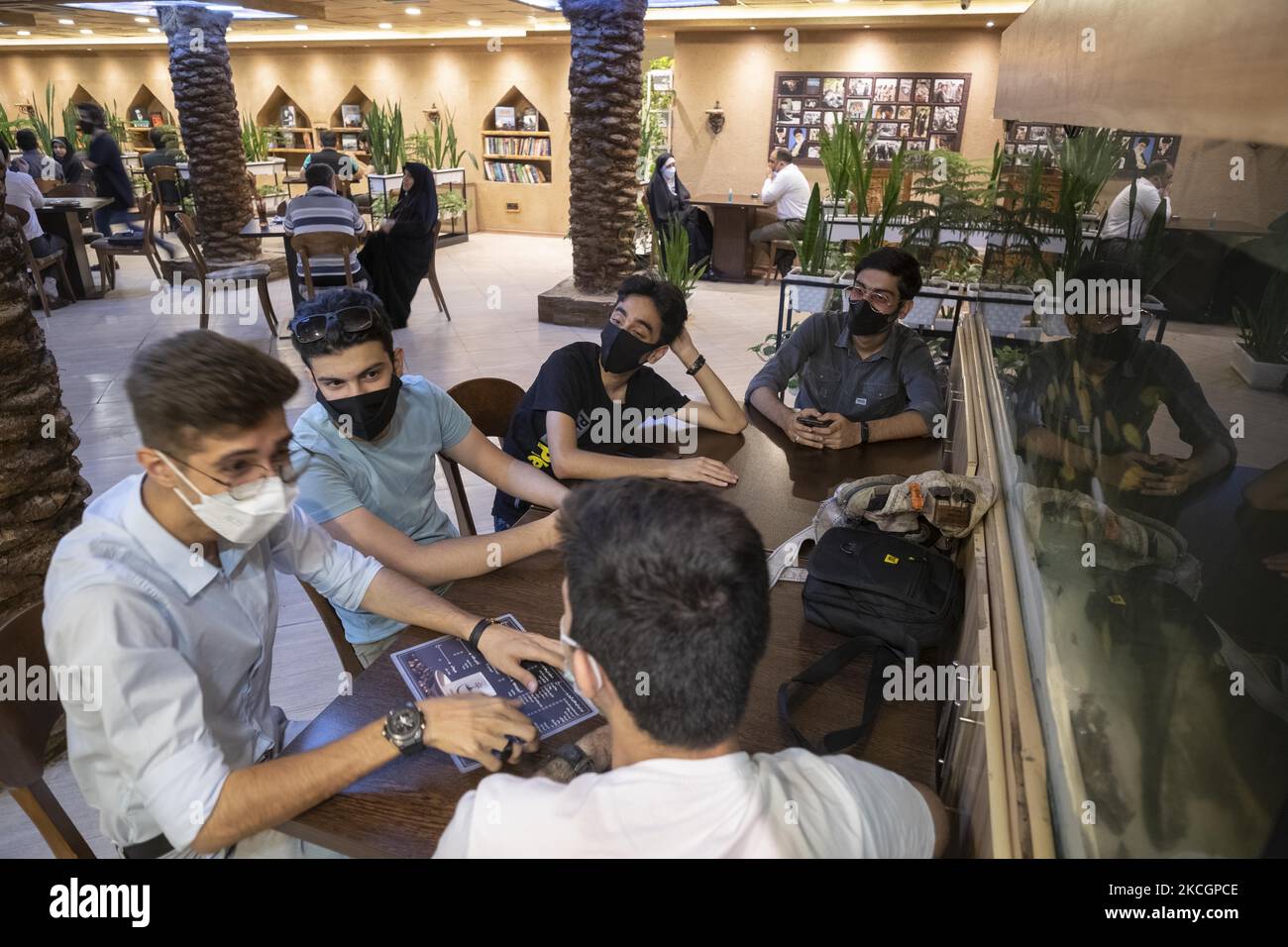 Iranian youths sit together at the Nakhlestan cafe in downtown Tehran, on July 1, 2021. Nakhlestan cafe (Palm Farm) has been organized and owned by the Owj, Islamic Revolutionary Guard Corps's (IRGS) Arts and Media Organization, that is located in downtown Tehran, Palm is the main symbol of the Iran-Iraq war (1980-88) martyrs. (Photo by Morteza Nikoubazl/NurPhoto) Stock Photo