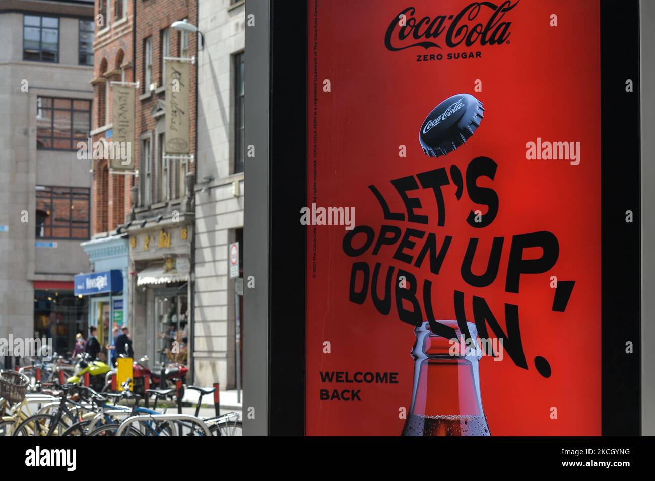 A street billboard with a CocaCola advert and the words 'Let's Open Up