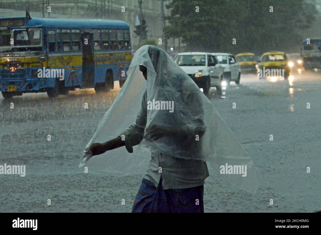 A man takes a plastic sheet as a protection during heavy rainfall in
