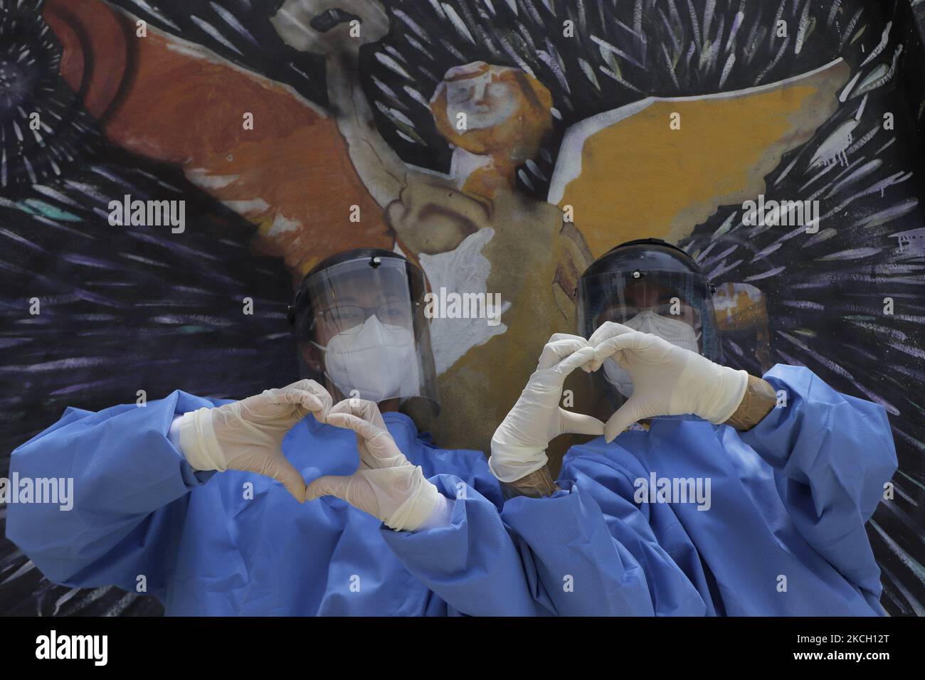 Medical personnel make the shape of a heart with their hands in front of a mural of the Angel of Independence located in La Gioconda Tláhuac, Mexico City, where rapid COVID-19 screening tests were carried out following the increase in coronavirus infections during the yellow epidemiological traffic light in the capital. (Photo by Gerardo Vieyra/NurPhoto) Stock Photo