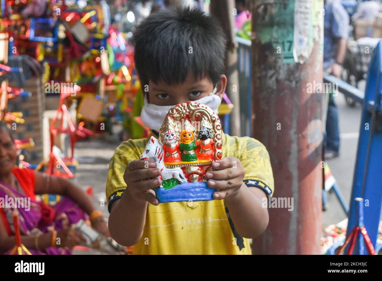 A kid shows off an idol of Jaganath , Subhadra and Balaram at a market place , ahead of rathyatra celebration in Kolkata , India , on 10 July 2021 . (Photo by Debarchan Chatterjee/NurPhoto) Stock Photo