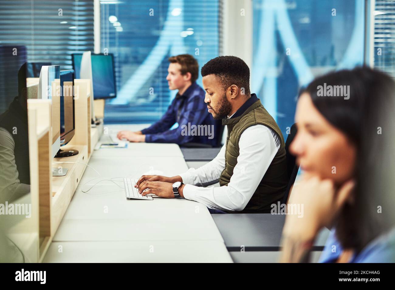 Hes a busy worker. a group of designers working on computers in an office. Stock Photo