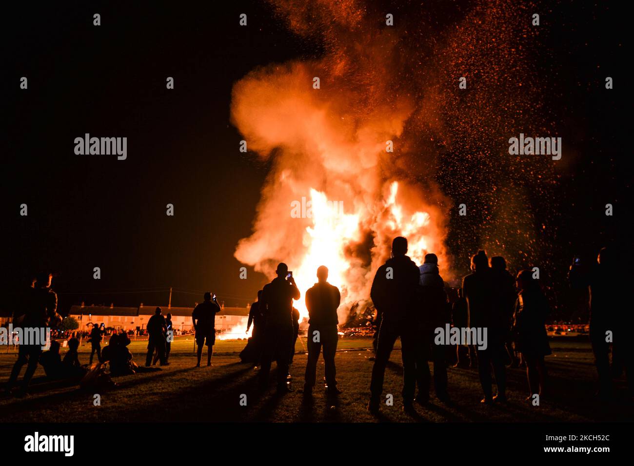 People watch a large bonfire during the Eleventh Night marking the start of the unionist Twelfth celebrations, in Craigy Hill, Larne. Tonight, large bonfires are lit in many Protestant loyalist neighbourhoods of Northern Ireland. Bonfires were originally lit to celebrate the Glorious Revolution (1688) and victory of Protestant king William of Orange over Catholic king James II at the Battle of the Boyne (1690), which began the Protestant Ascendancy in Ireland. On Monday, 12 July 2021, in Larne, County Antrim, Northern Ireland (Photo by Artur Widak/NurPhoto) Stock Photo