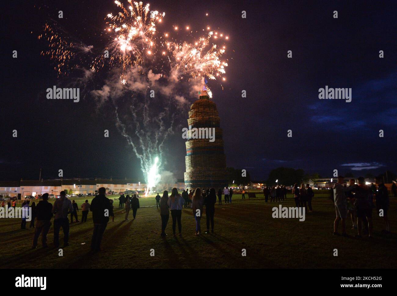 People watch fireworks as they wait for a large bonfire to be lit during the Eleventh Night celebration organized by members of the Loyalist Order in Craigy Hill, Larne. Tonight, large bonfires are lit in many Protestant loyalist neighbourhoods of Northern Ireland. Bonfires were originally lit to celebrate the Glorious Revolution (1688) and victory of Protestant king William of Orange over Catholic king James II at the Battle of the Boyne (1690), which began the Protestant Ascendancy in Ireland. On Monday, 12 July 2021, in Larne, County Antrim, Northern Ireland (Photo by Artur Widak/NurPhoto) Stock Photo