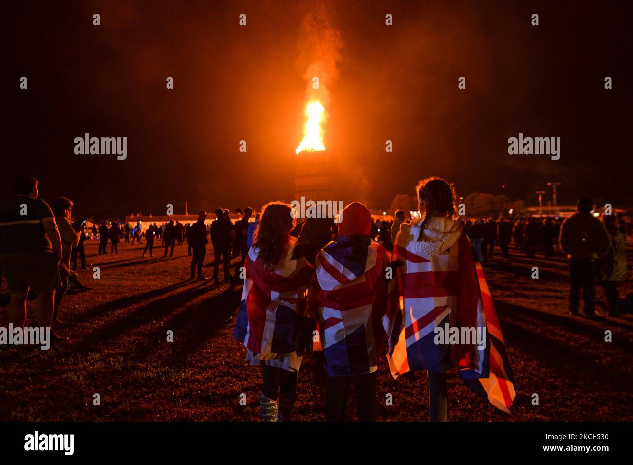 People watch a large bonfire during the Eleventh Night marking the start of the unionist Twelfth celebrations, in Craigy Hill, Larne. Tonight, large bonfires are lit in many Protestant loyalist neighbourhoods of Northern Ireland. Bonfires were originally lit to celebrate the Glorious Revolution (1688) and victory of Protestant king William of Orange over Catholic king James II at the Battle of the Boyne (1690), which began the Protestant Ascendancy in Ireland. On Monday, 12 July 2021, in Larne, County Antrim, Northern Ireland (Photo by Artur Widak/NurPhoto) Stock Photo