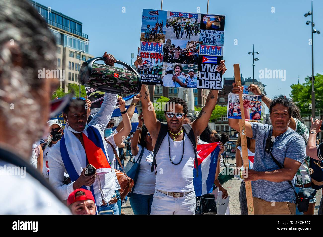Cuban people are wearing Cuban flags and holding placards while