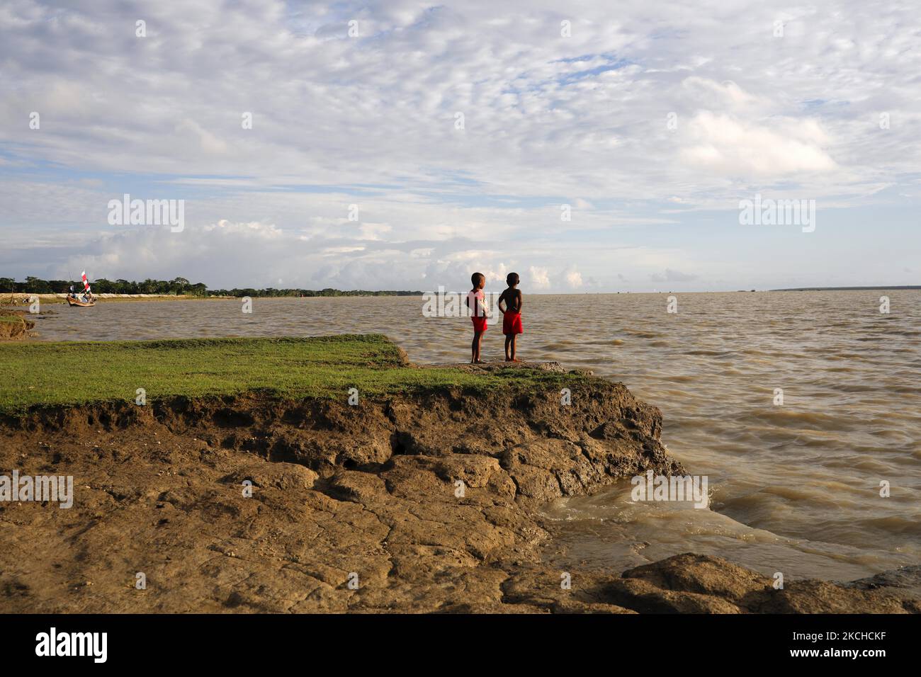 Two climate change victim boy stand front of river which has eroded their house at Monpura in Bhola, Bangladesh on July 18, 2021. Coastal areas in Bangladesh are on the 'front line' of climate change, directly affected by storm surges, drainage congestion, and sea level rise. Most of Bangladesh is less than ten metres above sea level, with almost ten per cent of the country below 1 metre, making it extremely vulnerable to increasing high tides. (Photo by Kazi Salahuddin Razu/NurPhoto) Stock Photo