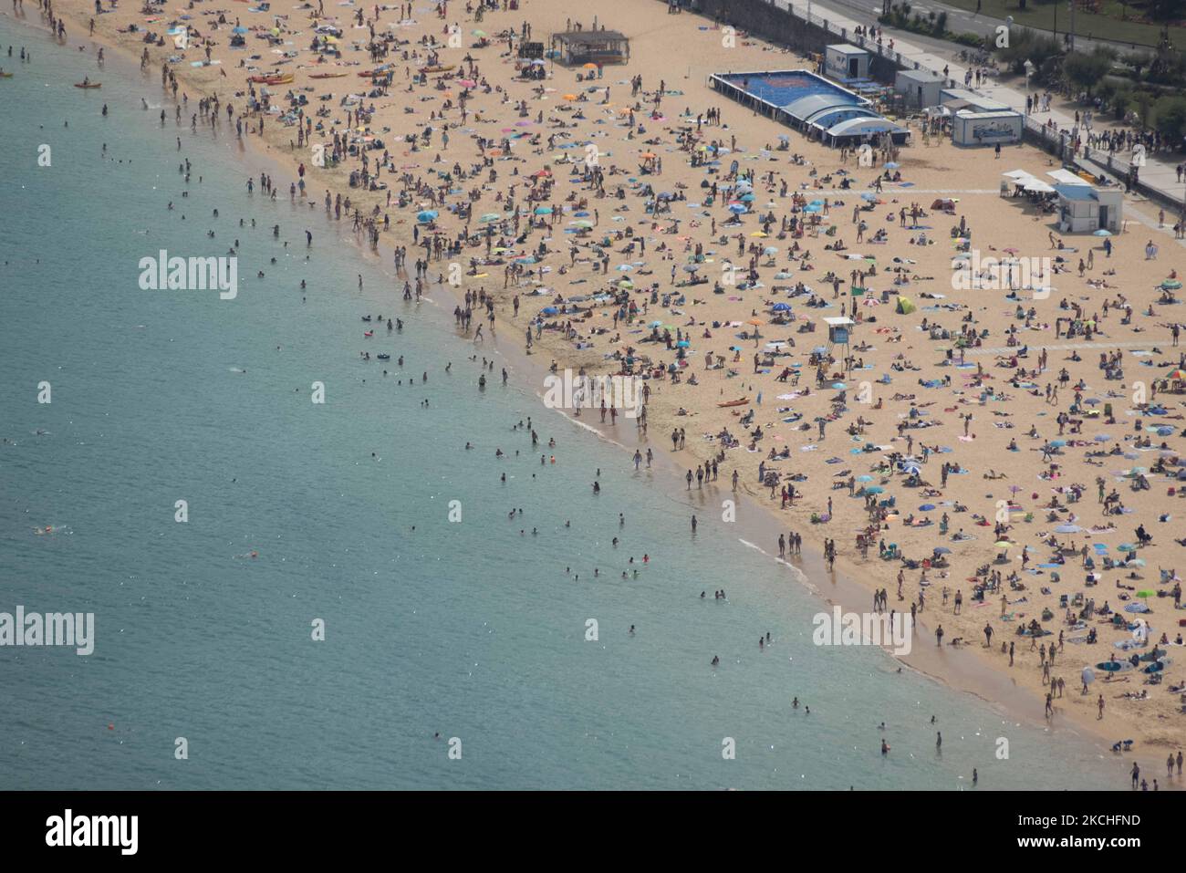 View of Ondarreta beach in San Sebastian crowded of people, on July 20, 2021. Beachgoers have gathered at the beaches on San Sebastian, Spain at temperatures of almost 30 degrees. Many tourists enjoy sun, sand, waves and sea at the beaches of Spain. (Photo by Manuel Balles/NurPhoto) Stock Photo
