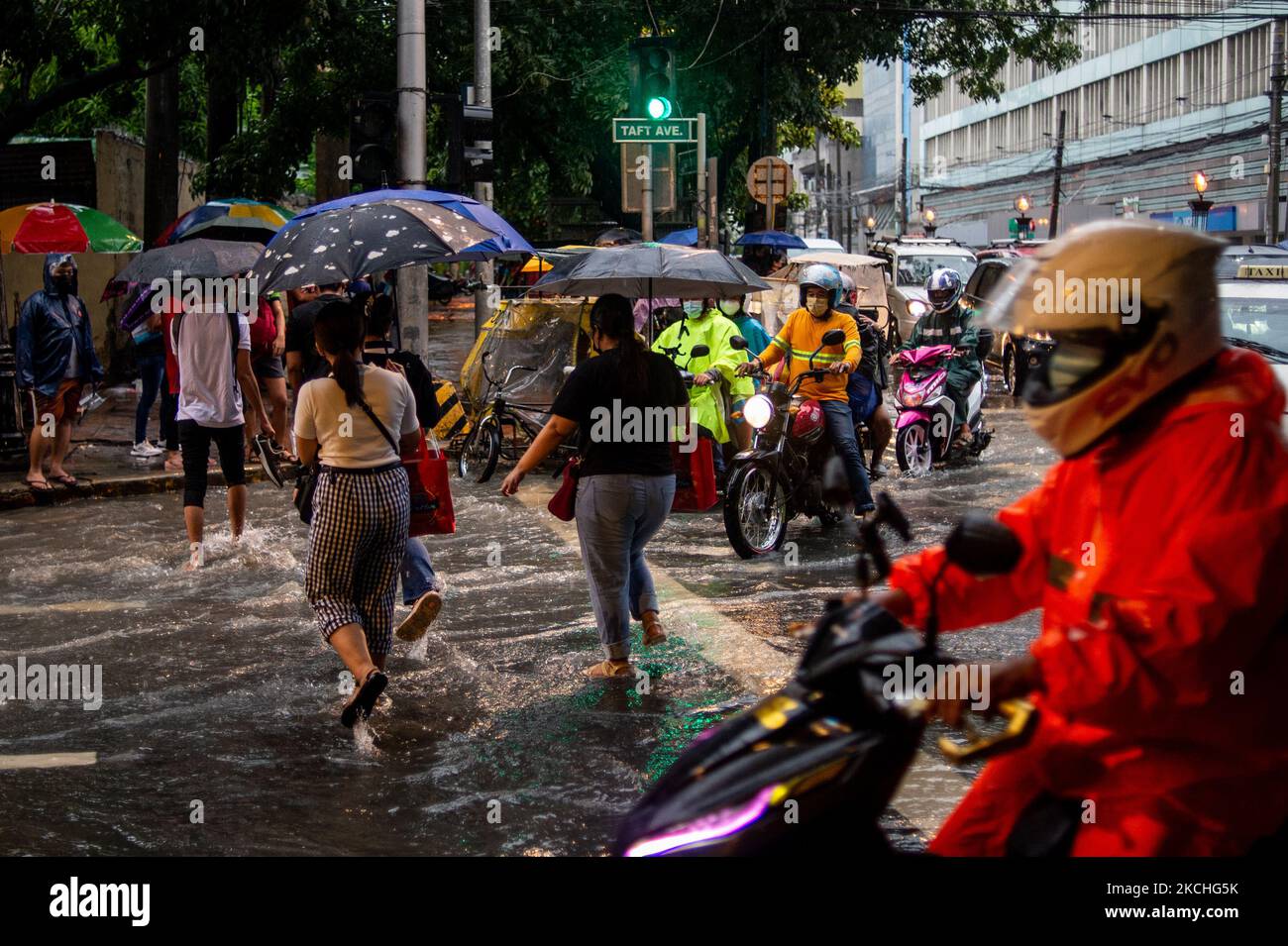 People wade through a flooded street following heavy rains in Manila ...