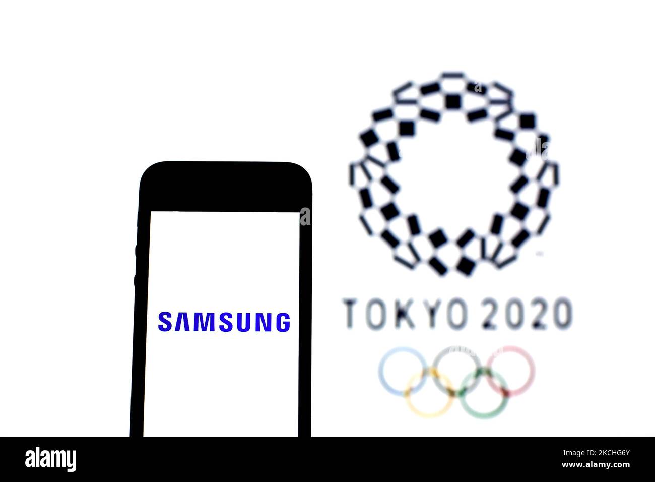 In this photo illustration a Samsung Electronics Co., Ltd. logo seen displayed on a smartphone with a Tokyo 2020 Olympic Games logo in the background. (Photo by DAX Images/NurPhoto) Stock Photo