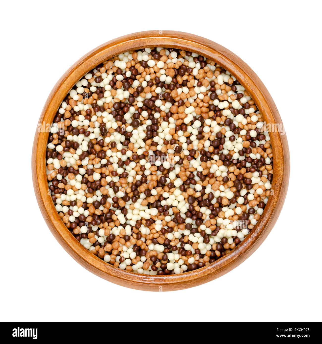 Mini chocolate crispy pearls mix, in a wooden bowl. Sweet crunchy cereal extrudate with a coating of dark, milk and white chocolate. Decoration. Stock Photo