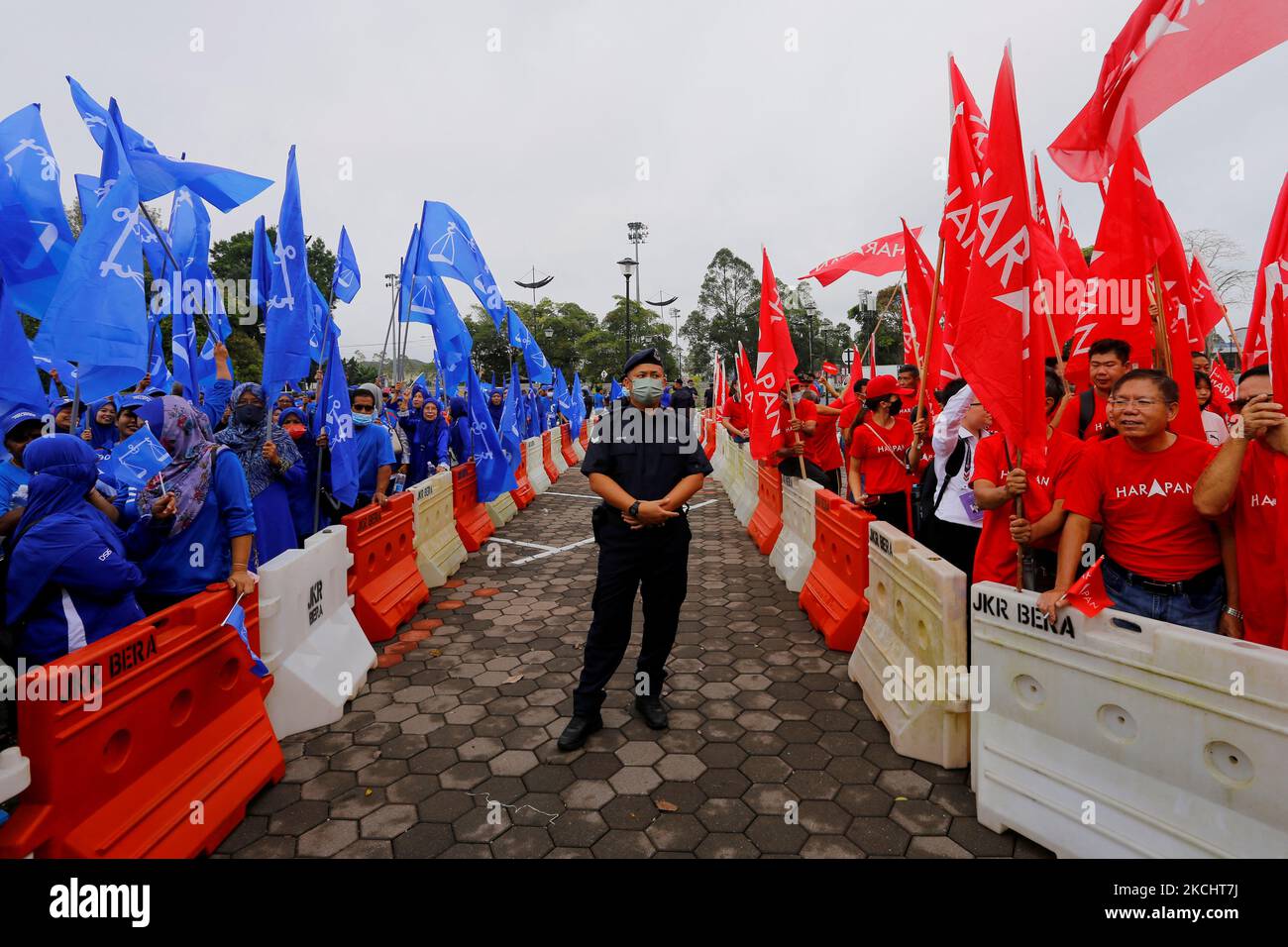 A police stands guard between supporters of The National Front coalition, Barisan Nasional, and The Alliance Of Hope, Pakatan Harapan, outside a nomination centre on nomination day in Bera, Pahang, Malaysia November 5, 2022. REUTERS/Lai Seng Sin Stock Photo