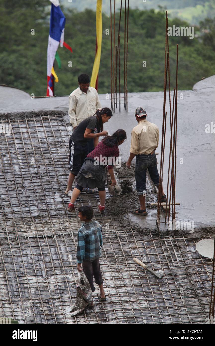 Workers and child labors cement a rooftop in preparation for construction for adding an additional level to a hotel in Pelling, Sikkim, India, on June 01, 2010. (Photo by Creative Touch Imaging Ltd./NurPhoto) Stock Photo