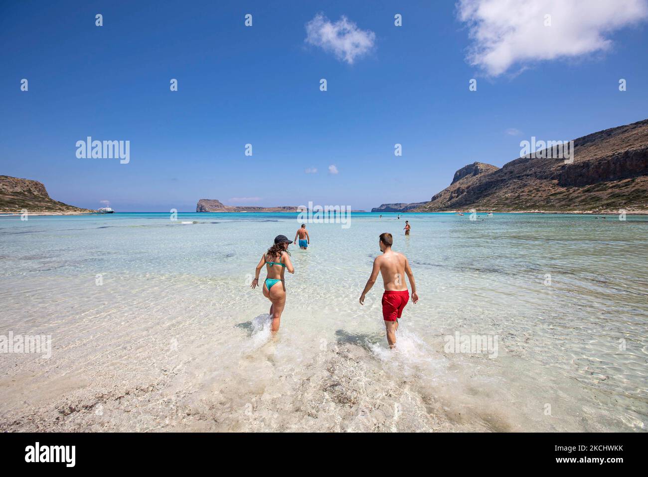 https://c8.alamy.com/comp/2KCHWKK/a-young-couple-enjoys-the-water-of-balos-as-they-run-or-walk-in-the-water-of-balos-beach-the-incredible-lagoon-with-the-pool-like-turquoise-exotic-and-tropical-water-of-the-mediterranean-sea-is-located-in-chania-region-in-crete-island-balos-is-one-of-the-most-visited-beaches-in-crete-and-popular-for-visitors-around-the-world-crystal-clear-water-the-lagoon-rocky-steep-mountains-a-beach-bar-providing-umbrellas-and-shadow-with-beverages-and-a-pirate-island-are-located-at-the-same-region-that-is-accessible-by-a-20-min-trek-or-boat-greece-is-trying-to-boost-its-tourism-and-give-privileges-2KCHWKK.jpg