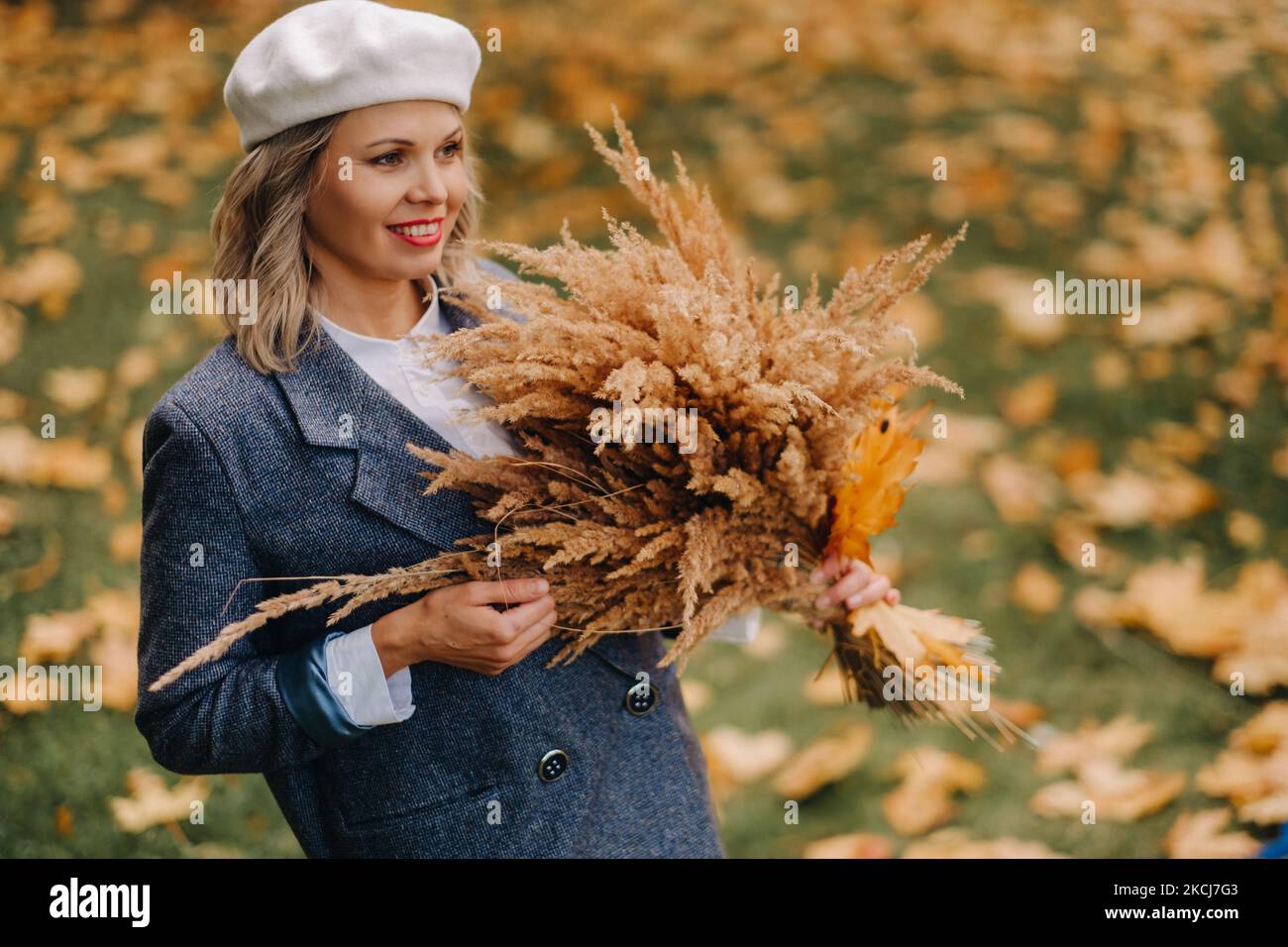 Portrait of a Girl in a jacket and birette with an autumn bouquet in an autumn park Stock Photo