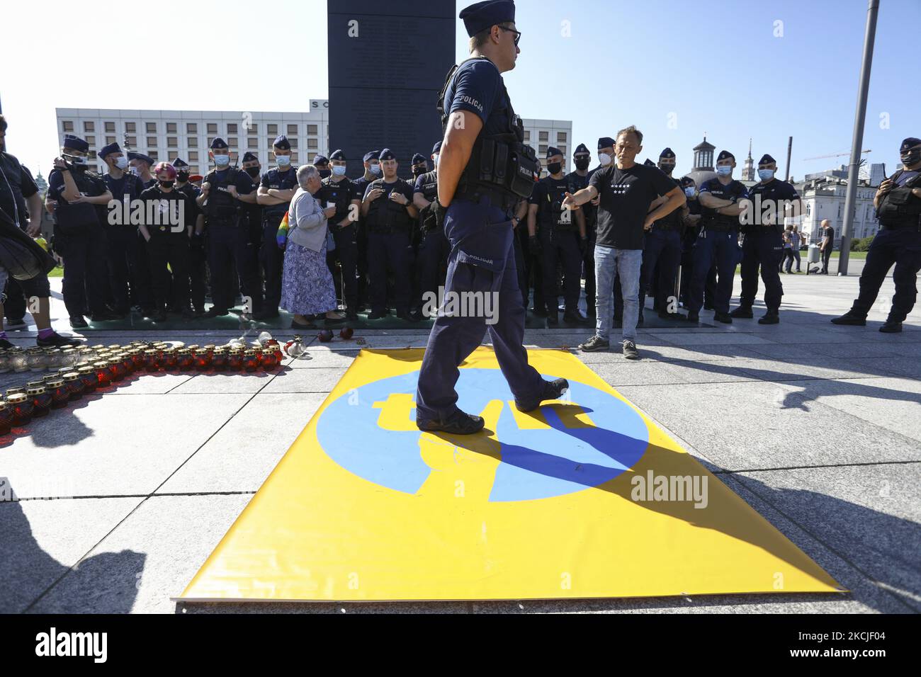 A policeman steps on a banner with the logo of broadcaster TVN modified to resemble a well known symbol of the anti-communist movement in Warsaw, Poland on August 10, 2021. American owned broadcaster TVN's license in Poland will expire at the end of September and the government has indicated it will not renew the license citing converns over it's forerign ownership. Critics argue the non-renewel is a move by the government to shut down critical media outlets. A new bill proposed by lawmakers prohibiting ownership of radio and television outlets by proprietors outside of the European Economic A Stock Photo