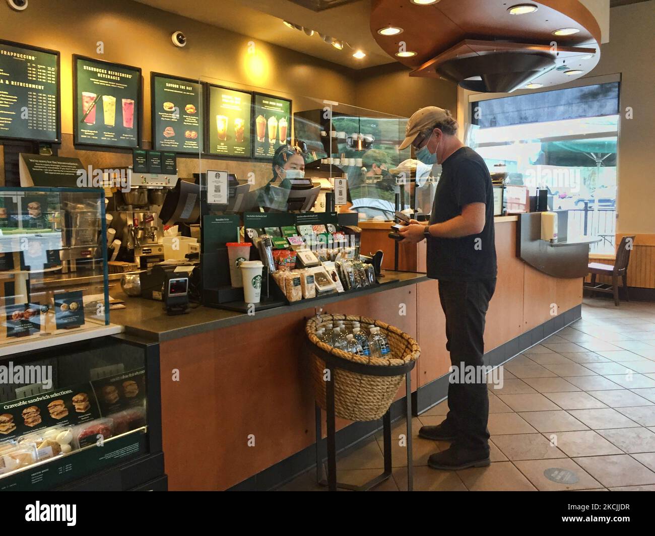 Man orders a coffee at a Starbucks following the recent reopening of restaurants allowing dine-in services in Toronto, Ontario, Canada on August 10, 2021. Officials declared that Canada is now in the 4th wave of the novel coronavirus (COVID-19) pandemic as cases spike across much of the country following the loosening of health measures meant to keep the virus at bay and the recent reopening following the last lockdown. The fourth wave of the COVID-19 pandemic is driven by the Delta variant (the variant that originated in India) which has become the dominant strain of the virus across most of  Stock Photo