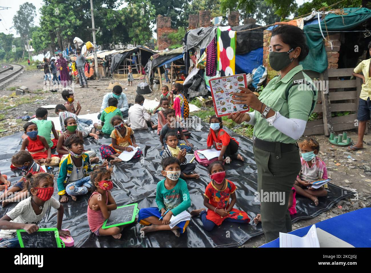 A lady volunteer of South West traffic guard teaching basic alphabets and numbering to students of a slum , in Kolkata , India , on 13 August 2021 .A special class was organized by South west traffic guard to students belonging from slums of south Kolkata who cannot avail online classes or tuitions as all schools remain shut due to the pandemic. (Photo by Debarchan Chatterjee/NurPhoto) Stock Photo