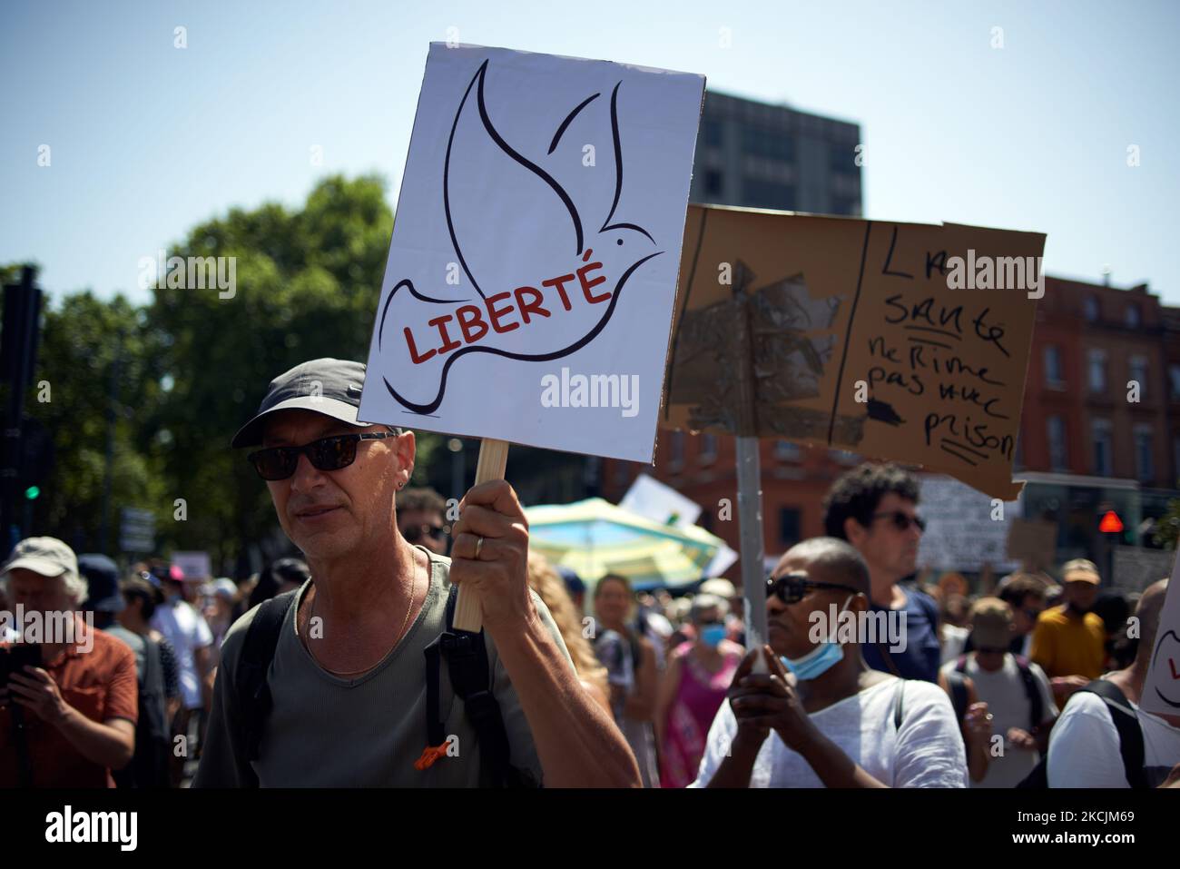 A protester holds a drawing of a dove and reading 'Liberty'. Thousands of protesters took to the streets in Toulouse against the near mandatory vaccination and against the mandatory health pass after Macron's speech on July 12th. More then 220,000 people demostrated across France. On July 12th, Macron announced the health pass will be mandatory for entry to a wide array of public venues such as cafes, theaters, concerts hall, cinemas, shopping malls, public transportation, swimming pools, and even hospitals unless a critical situation, etc. The prohibition for public spaces for unvaccinated pe Stock Photo