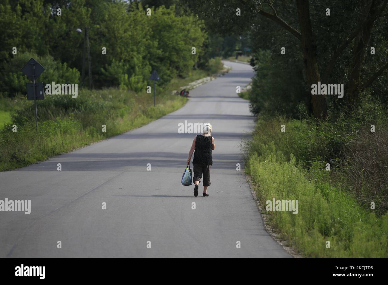 Woman walks by country road near Krynki on August 14, 2021. (Photo by Maciej Luczniewski/NurPhoto) Stock Photo