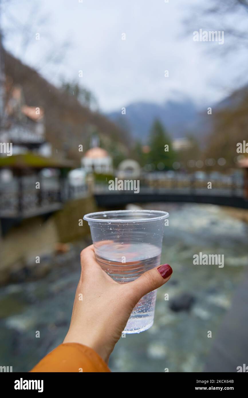 Firstperson view holding a glass of pure water from a mountain spring