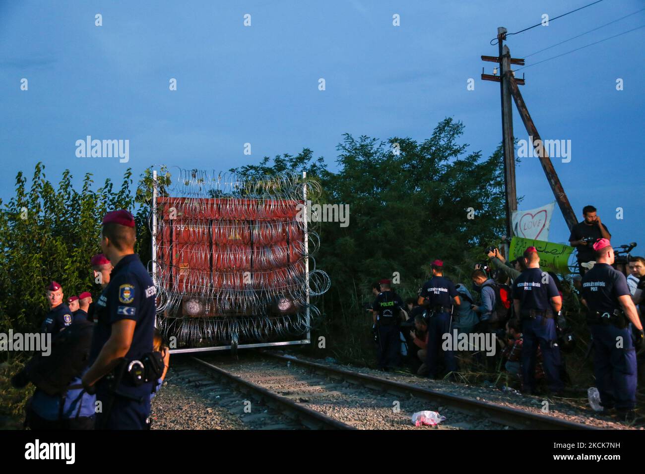 Hungarian police officers guard the area as a rail wagon prepared with barbwire arrives to seal the border fence between Serbia and Hungary at the border line in Roszke, southern Hungary on September 14, 2015. A razor-wire barrier along the 175km border with Serbia is aimed at keeping out refugees entering from Serbia (Photo by Beata Zawrzel/NurPhoto) Stock Photo