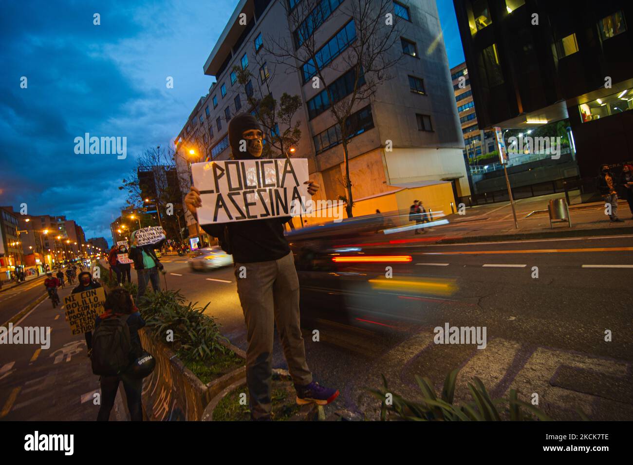 A demonstrator holds a sign that reads 'Killer Police' as cars pass by during a student rally of the Universidad Distrital, after Esteban Mosquera, a social leader and community member was killed two years after loosing his eye on a police brutality case, in Bogota, Colombia on August 26, 2021. (Photo by Sebastian Barros/NurPhoto) Stock Photo