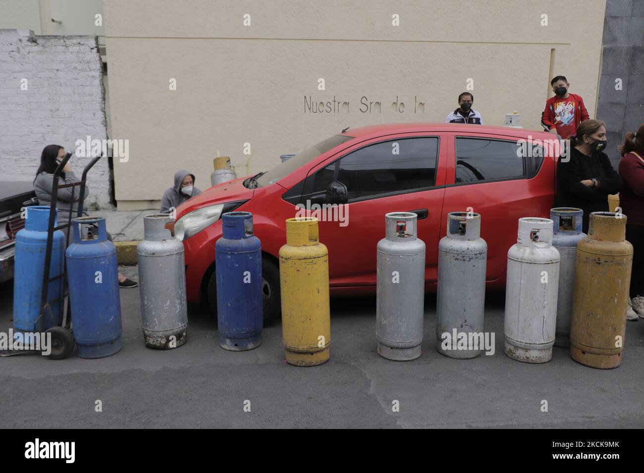 A group of people with gas tanks awaits the start of Gas Bienestar