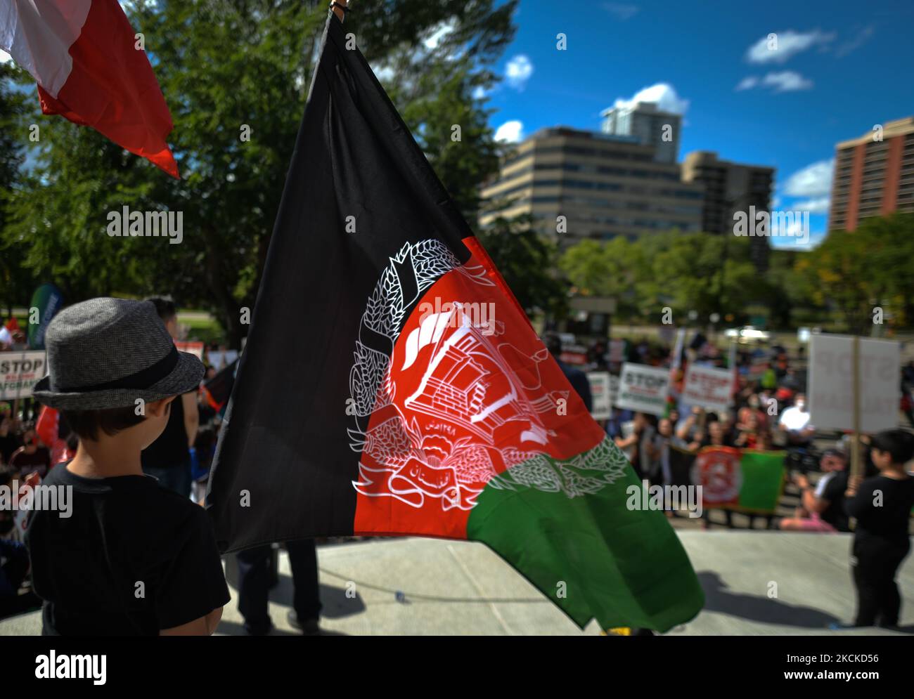 A young boy holds a striped black-red-green national flag of Afghanistan. Members of the local Afghan diaspora, activists and local supporters seen in front of the Alberta Legislature Building during the STOP KILLING AFGHANS! protest organised today by the Global Movement of Peace for Afghanistan. Saturday, August 28, 2021, in Edmonton, Alberta, Canada. (Photo by Artur Widak/NurPhoto) Stock Photo