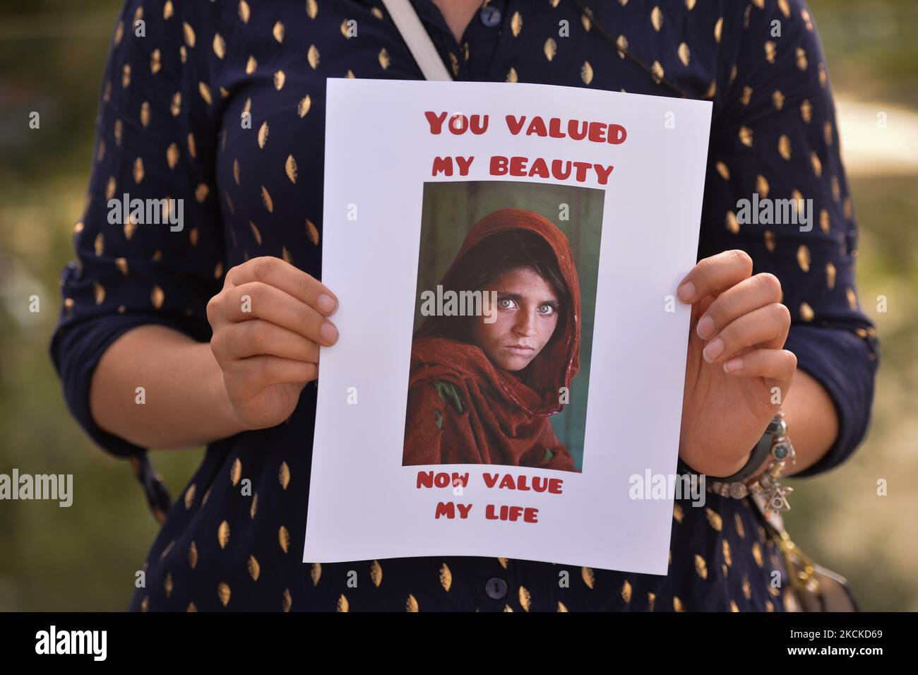 A protester holds the famous Afghan Girl photo - a 1984 photographic portrait of Sharbat Gula by photojournalist Steve McCurry with the words 'You Valued My Beauty, Now You Value My Life.' Members of the local Afghan diaspora, activists and local supporters seen in front of the Alberta Legislature Building during the STOP KILLING AFGHANS! protest organised today by the Global Movement of Peace for Afghanistan. Saturday, August 28, 2021, in Edmonton, Alberta, Canada. (Photo by Artur Widak/NurPhoto) Stock Photo