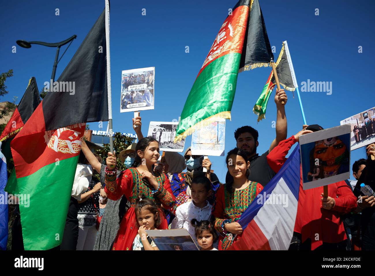 Young afghan girls wear traditional dress and hold Afghanistan'flag. Dozens of members of the Afghani community of Toulouse organized a gathering in Toulouse to raise awereness about the Afghanistan's situation. After the Trump's decision (and applied by Biden) to pull out all US soldiers from Aghanistan after 20 years of war, the lightning advance of Talibans towards Kabul and the seizure of it, thousands of Afghans trying to escape were stranded at the Kabul's airport. They want to escape the Talibans regime. Thus, Afghans living in Toulouse gathered to inform about the Talibans regime and t Stock Photo