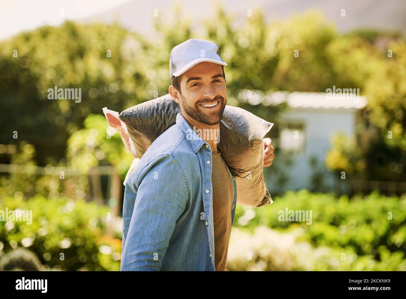 Its a hands-on kind of job. Portrait of a happy young farmer carrying a ...