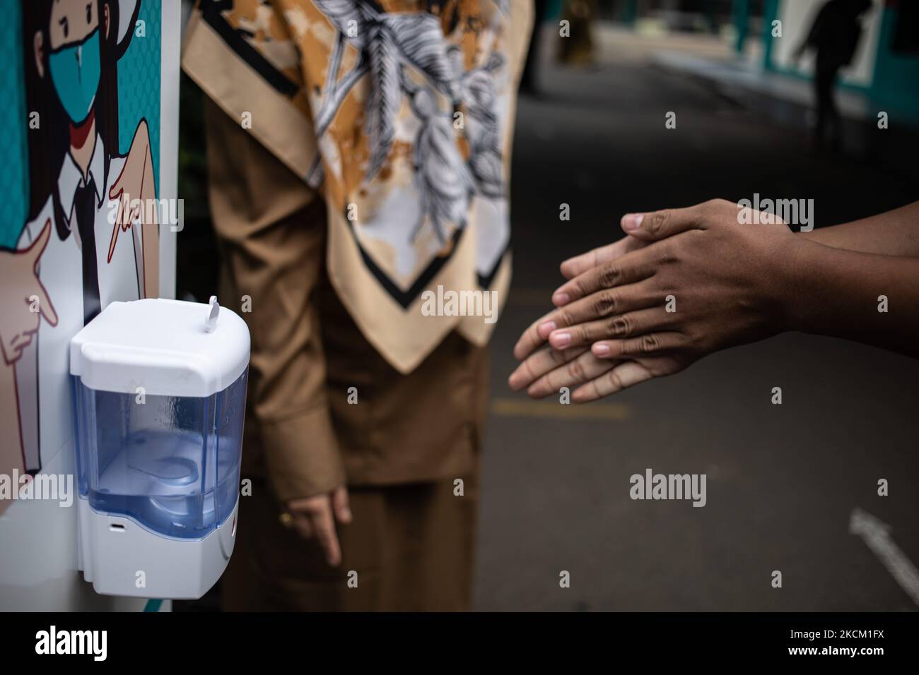 A student disinfects his hands before entering the classroom, in South Tangerang, Indonesia, on September 6, 2021. Indonesia government eased the Covid-19 restrictions alloing face-to-face learnings with a limited number of students. (Photo by Donal Husni/NurPhoto) Stock Photo