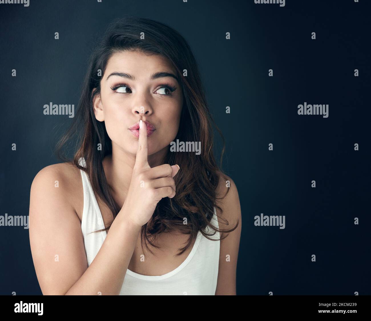 Im not saying a word. Studio shot of a beautiful young woman posing with her finger on her lips. Stock Photo
