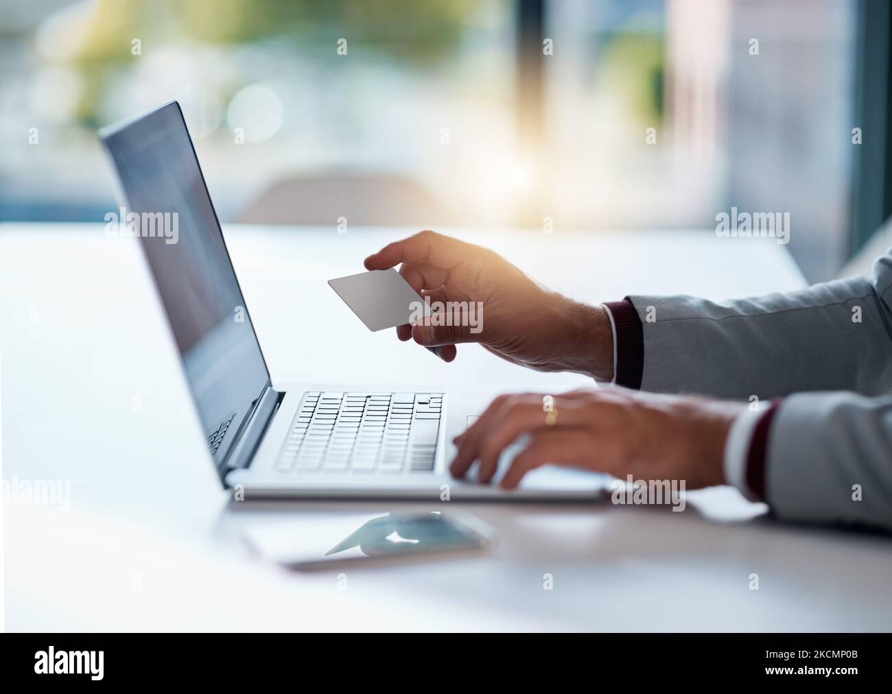 Making transfers with ease. an unrecognizable businessman holding his credit card while using a laptop at his desk. Stock Photo
