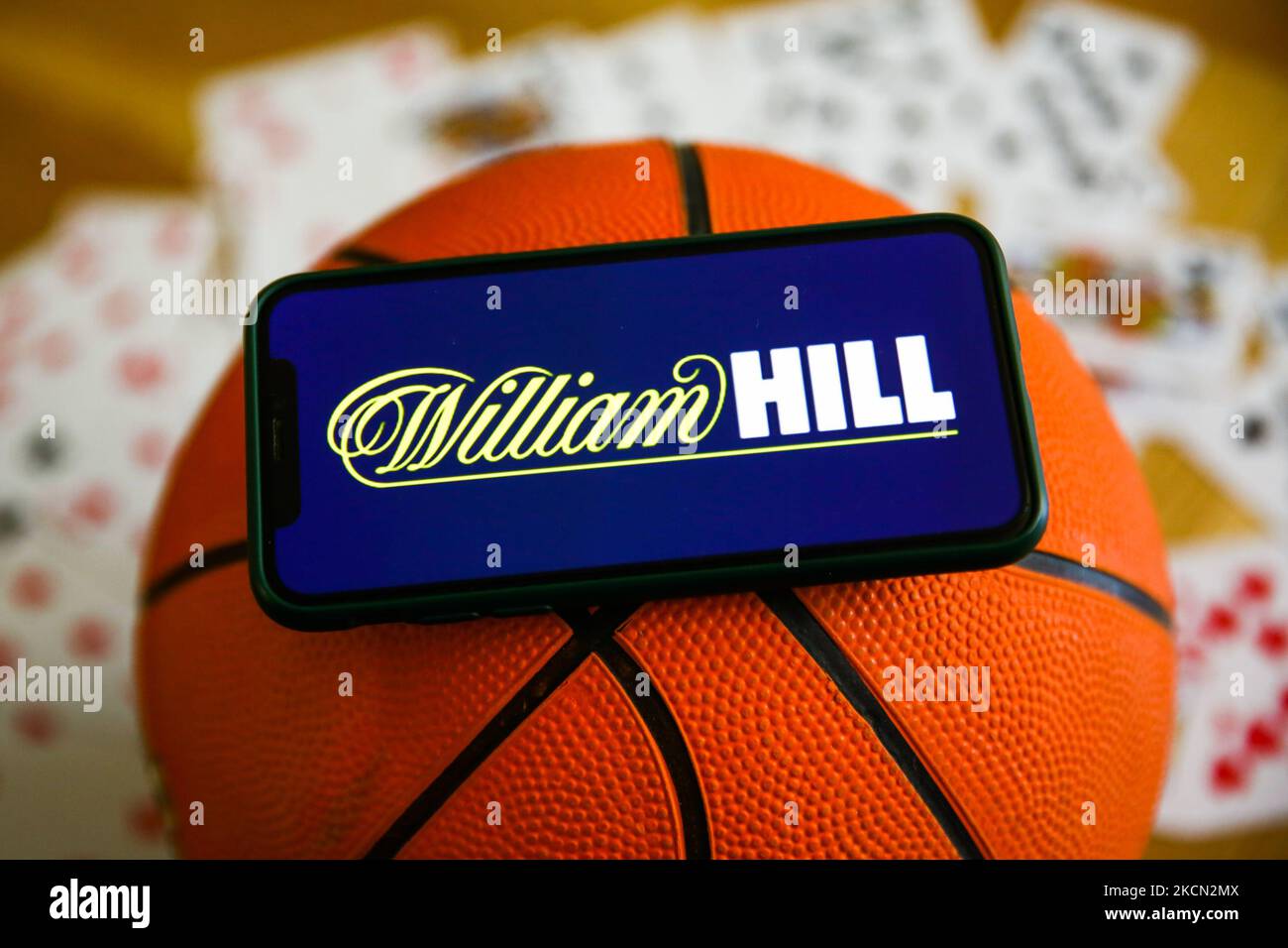 William Hill logo displayed on a mobile phone, basketball and playing cards are seen in this illustration photo taken in Krakow, Poland on September 21, 2021. (Photo by Jakub Porzycki/NurPhoto) Stock Photo